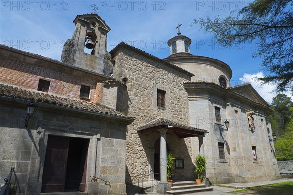 Stone church with bell tower and cross, surrounded by nature and under a blue sky, Santuario de San