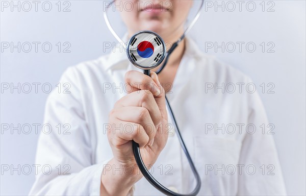 Female doctor holding stethoscope with South Korean flag. South Korean Health and Care concept