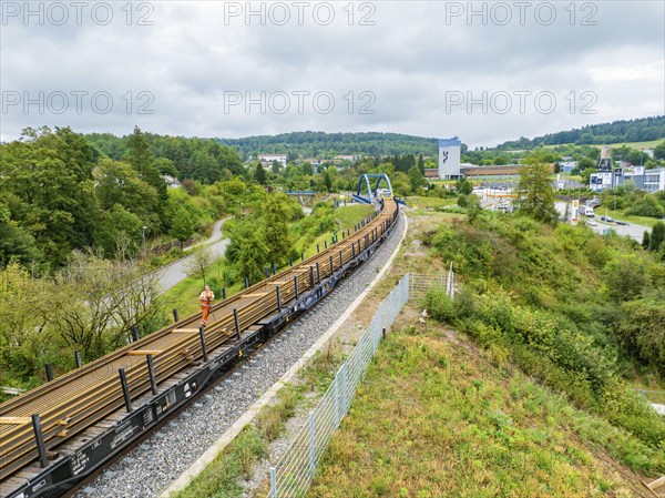 Train on railway line next to green countryside and city view, track construction, rail delivery