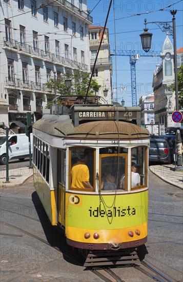 Yellow-green tram bends around a curve through the city, Tram, Line 28, Carros eléctricos de