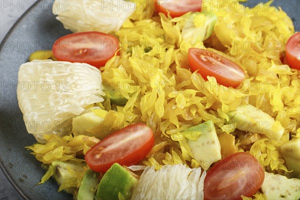 Fried pomelo with tomatoes and avocado on gray concrete background, close up, myanmar food