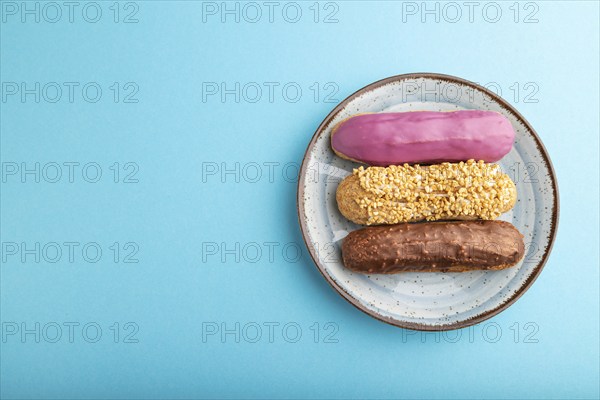 Set of eclair, traditional french dessert on ceramic plate on blue pastel background. top view,