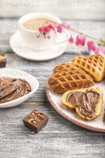 Homemade waffle with chocolate butter and cup of coffee on a gray wooden background. side view,