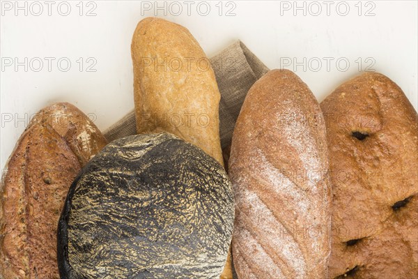Different kinds of fresh baked bread on a white wooden background. top view, flat lay, close up