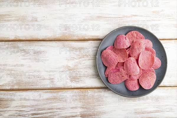 Red potato chips with herbs and tomatoes on white wooden background. Top view, flat lay, copy space