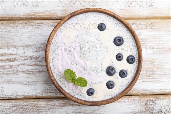 Yogurt with blueberry in wooden bowl on white wooden background. top view, flat lay, close up