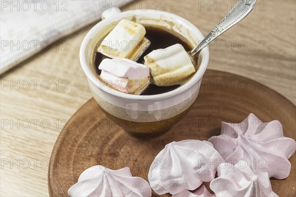 Chewing marshmallows, meringue and coffee cup on a wooden board and linen tablecloth