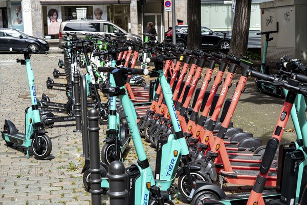 Electric scooters, e-scooters are parked in large numbers on the Burgmauer road, in front of