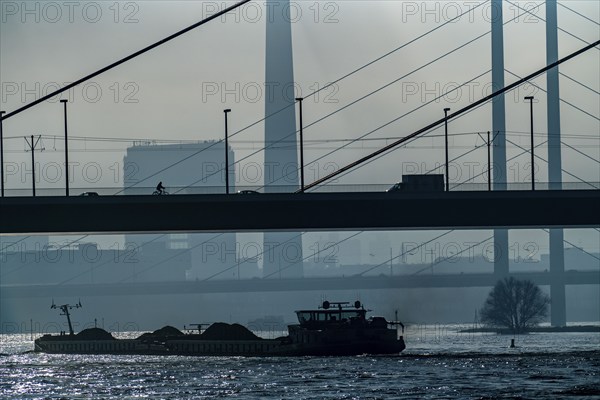 Dense fog slowly lifting, cargo ships on the Rhine near Düsseldorf, in front the Oberkassler