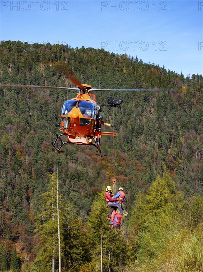 2 mountain rescuers of the Bavarian Mountain Rescue Service are winched by the on-board mechanic of