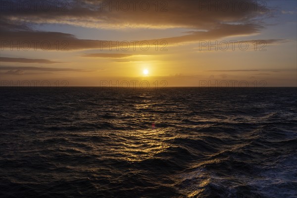 Sunset over a calm sea with clouds and a shimmering orange sky, Celtic Sea