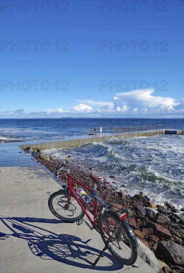 Sun shining on a bicycle on a coastal promenade with a view of the sea and waves, Tönsberg,