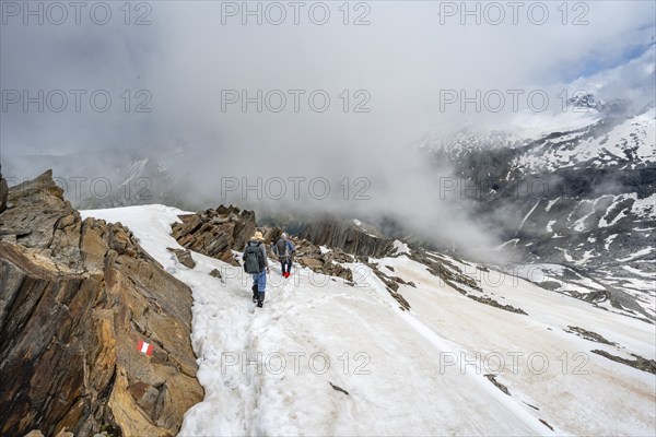 Mountaineer on a rocky ridge with snow, descent from the summit of Schönbichler Horn, view of