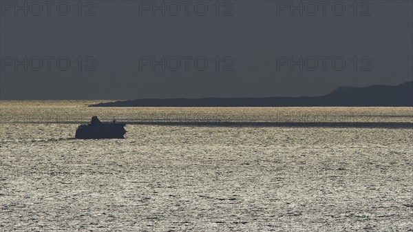 Silhouette of a ship on the glittering sea at sunset, calm evening mood, departure of the Bluestar