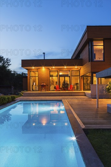 Rear of modern cube style home with stained horizontal wood cladding, in-ground swimming pool and
