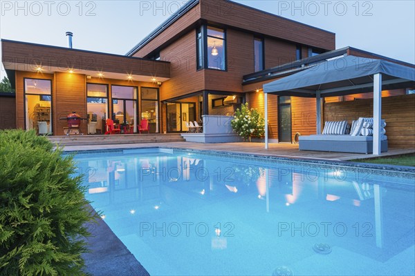 Rear of modern cube style home with stained horizontal wood cladding, in-ground swimming pool and