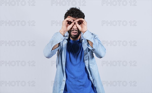 Man making binoculars gesture isolated. Curious man making binoculars gesture isolated