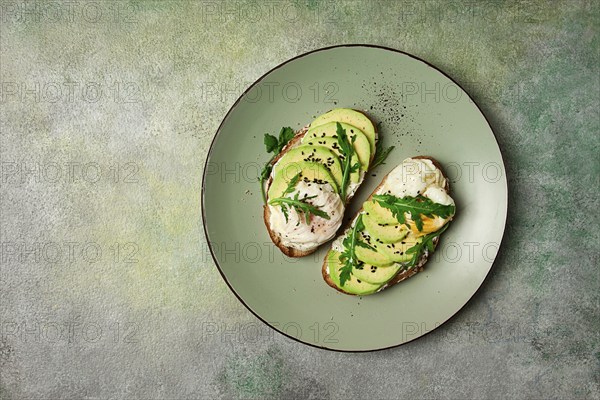 Sandwich with cream cheese, sliced avocado and boiled egg, arugula, on grainy bread, homemade,
