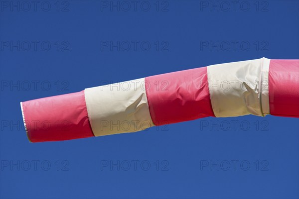 A red and white windsock blows against a clear blue sky, Germany, Europe