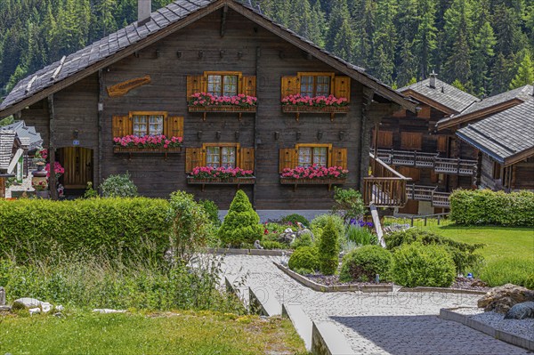 Modern chalet with wooden shingle roof and flower boxes in front of the windows, Grimentz, Val