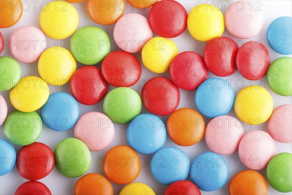 Colorful multicolored chocolate candy dragees on white background. Top view, close up