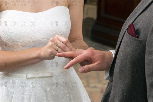 The bride slips the wedding ring over the groom's ring finger during the wedding ceremony,