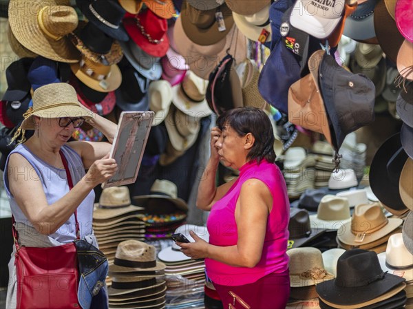 Oaxaca, Mexico, A woman sells a hat to a tourist at the Benito Juarez Market. Opened in 1894, it is