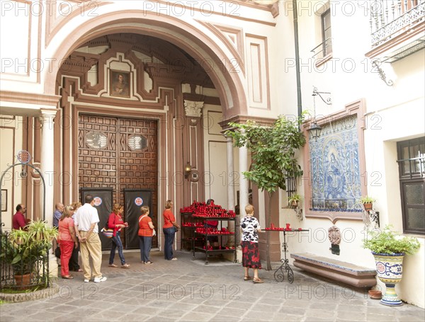People lighting red candles in the courtyard of the church of San Antonio Abad, Seville, Spain,