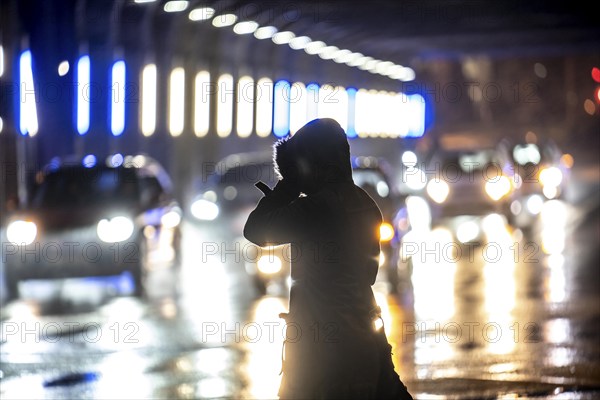Illuminated subway at the main railway station, pedestrians at a pedestrian crossing, rainy