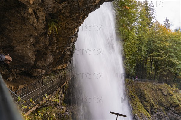 An impressive waterfall under a rock overhang in autumn forest, Lake Brienz, Switzerland, Europe