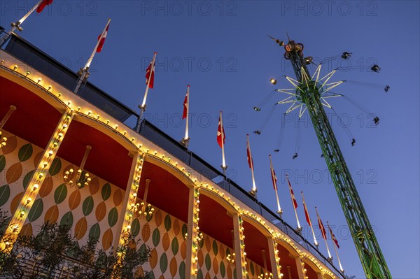 Building with illuminated Danish flags and Star Flyer chain carousel with passengers at high