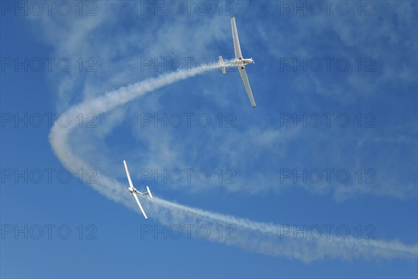Stunt aerobatic plane performing stunts in blue sky with smoke trail. Concept of teamwork,