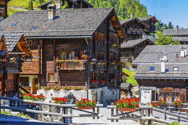 Old wooden houses with wooden shingle roofs and flower boxes in the historic centre of Grimentz,