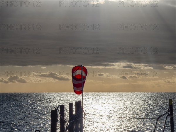 Windsock at sunrise over the sea in the Strait of Magellan, Punta Arenas, Chile, South America