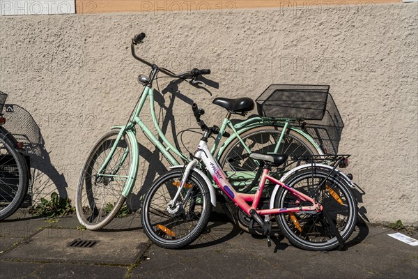 A child's bicycle and a bicycle for an adult are parked together, parked