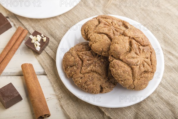 Homemade oatmeal cookies with a cup of cocoa on a linen textile and white wooden background. side