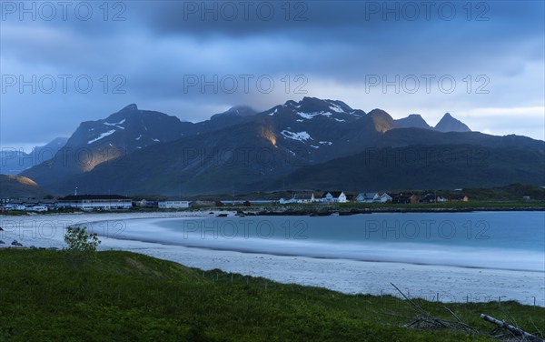 The village of Ramberg with sea and sandy beach. Mountains behind it. Individual sun spots in the