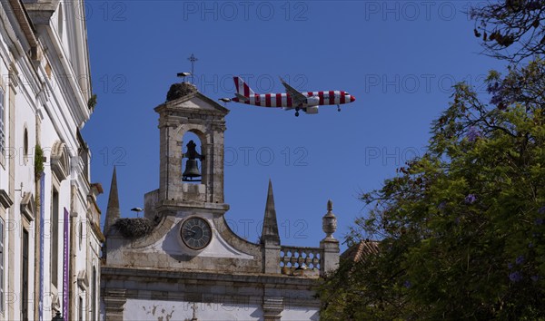 Condor holiday plane, aeroplane, flies low over city archway, stork nests, nest, storks nesting on