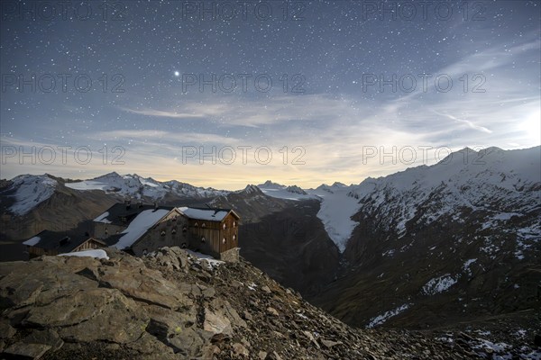 Mountain landscape under a starry sky, night shot, mountain hut Ramolhaus in autumn with snow, view