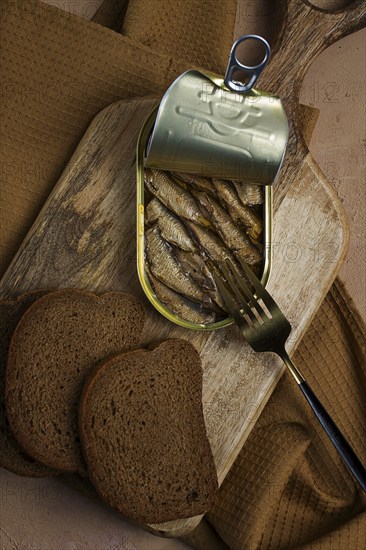 Sprats in butter, with black bread, canned smoked fish, open, close-up, top view, no people