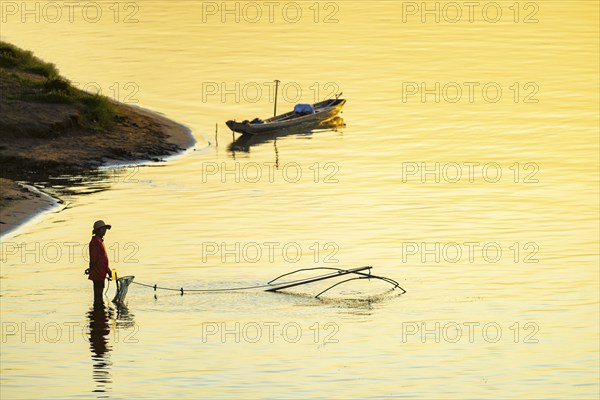 Fisherman with a sinking net at sunset on the Mekong, Luang Prabang, Laos, Asia