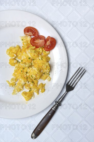 Scrambled eggs and tomatoes on a plate and fork