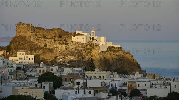Whitewashed houses and an old castle on a hill at twilight overlooking the calm sea, morning light,