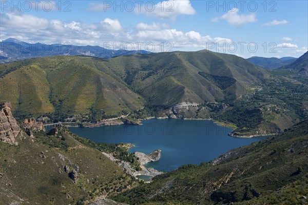 Large blue lake, surrounded by green mountains and hills, under a cloudy sky, reservoir, Embalse de