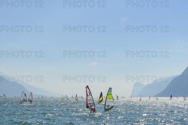 People windsurfing on a sunny day with clear blue skies and mountain backdrop, Lake garda, Torbole,