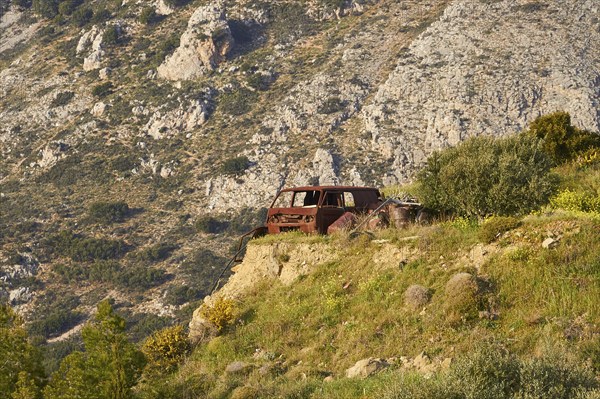 Abandoned rusted car on a rocky meadow in front of majestic mountains, Vehicle wreck, Crete, Greek