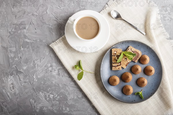 Chocolate truffle on blue ceramic plate and a cup of coffee on gray concrete background. top view,