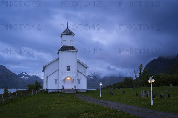 The white church of Gimsoy (Gimsoysand church) by the sea. A path leads to the church. The church
