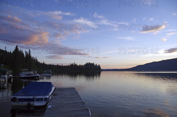 A calm lake at sunset, a jetty with boats and idyllic nature in the background, St. George, British