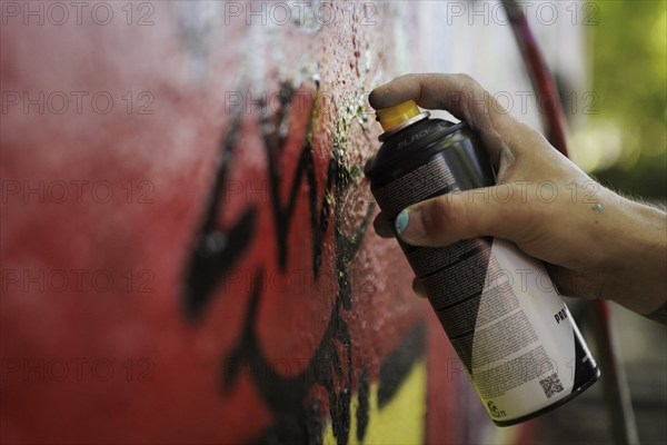 A man sprays graffiti on a wall with a spray can. Berlin, 14.08.2024